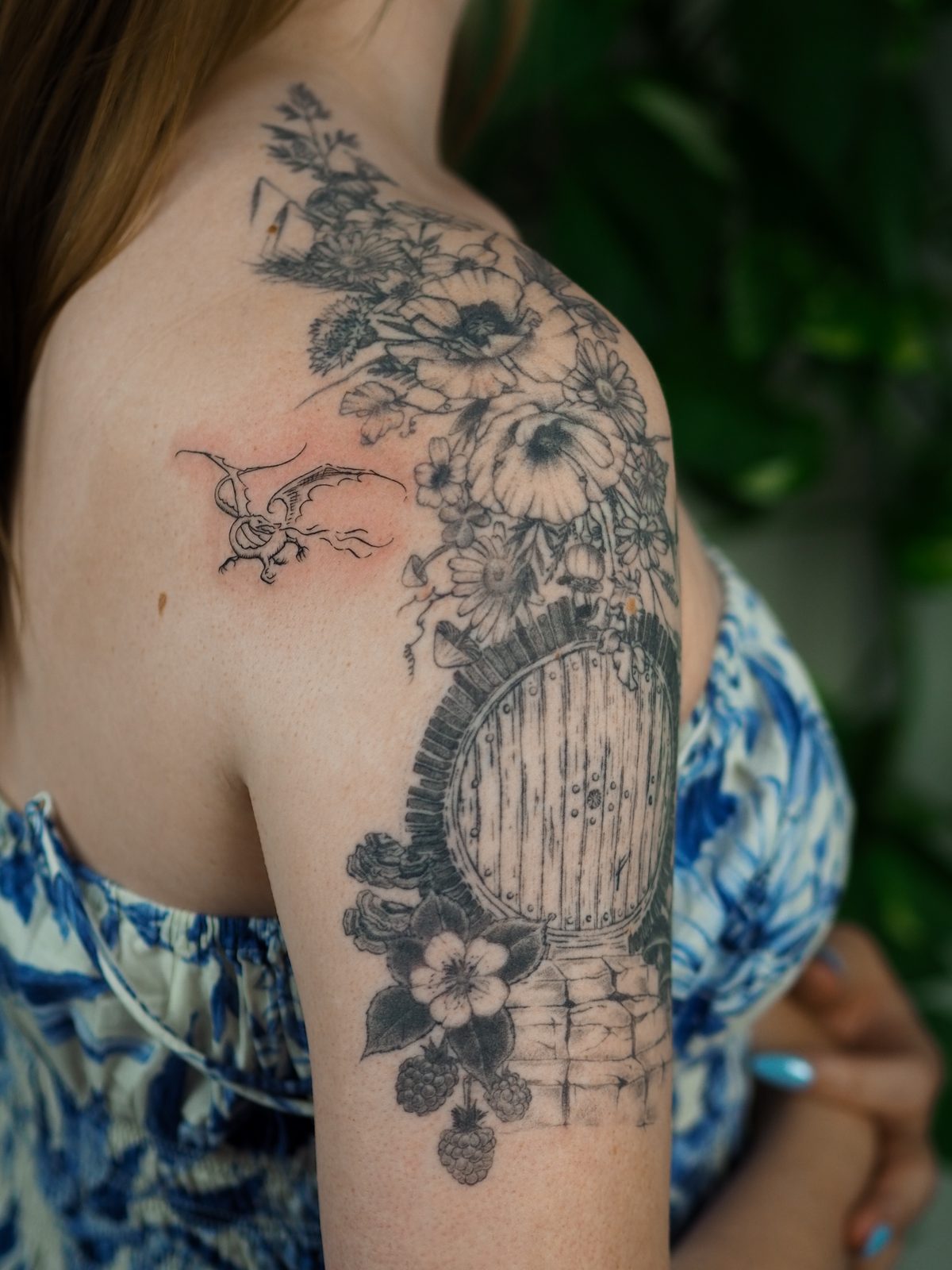 Tatuagem de porta de hobbit com flores e dragão no ombro