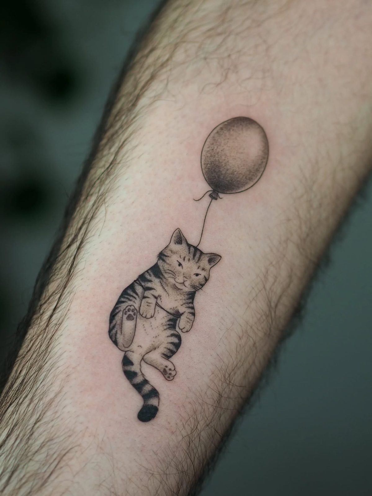 Tatuagem de gato com balão no antebraço